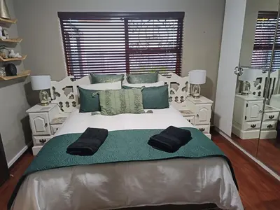 a bedroom with a large bed with green and white at Urban Oasis Cape Town in Cape Town