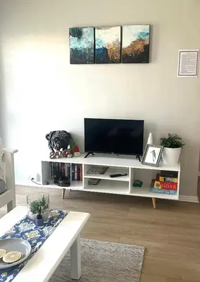 a living room with a television on a white entertainment center at Serenity self-catering 2-bed unit in Hermanus