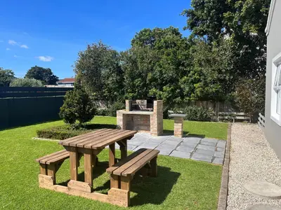 a picnic table and a fire place in a yard at Serenity self-catering 2-bed unit in Hermanus