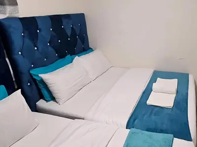 a bed with a blue headboard in a room at Goshen Lodge Spencer in Cape Town
