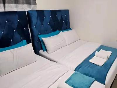a small bedroom with two beds and a headboard at Goshen Lodge Spencer in Cape Town