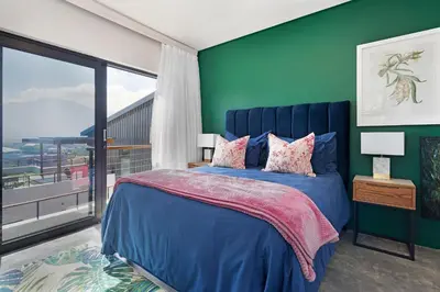 a bedroom with a blue bed and a green wall at The Baydreamer, where the view soothes your soul in Pringle Bay