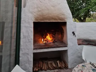 a stone pizza oven with a fire in it at Champagne De Kleijne Bos Pty Ltd in Paarl