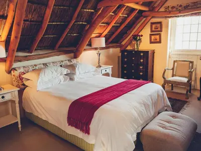 a bedroom with a large bed and a chair at Champagne De Kleijne Bos Pty Ltd in Paarl