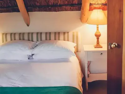 a bedroom with a bed and a lamp on a night stand at Champagne De Kleijne Bos Pty Ltd in Paarl