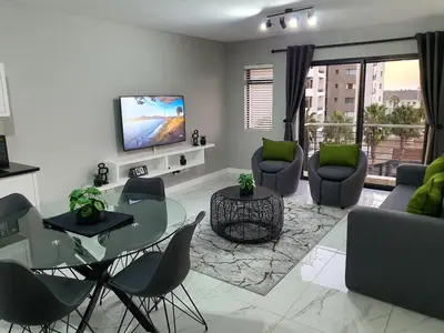 a living room with a glass table and chairs at Knightsbridge Superior Apartments in Cape Town
