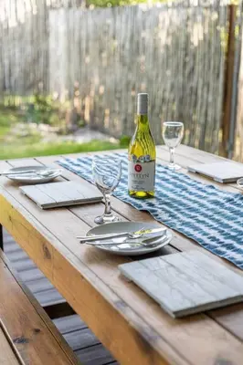 a wooden table with a bottle of wine and glasses at Pringle Bay getaway - 2 bedroom garden apartment in Pringle Bay