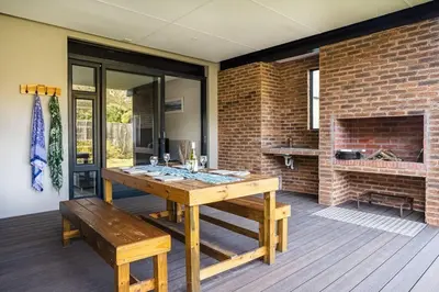a dining room with a wooden table and a brick wall at Pringle Bay getaway - 2 bedroom garden apartment in Pringle Bay