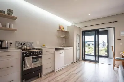 a large kitchen with white cabinets and an open door at Pringle Bay getaway - 2 bedroom garden apartment in Pringle Bay