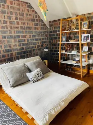 a bed in a room with a brick wall at Secure, luxurious with lovely views in Pringle Bay