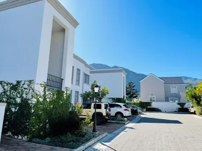 a white house with cars parked in a driveway at Spacious, Modern & Convenient in Franschhoek
