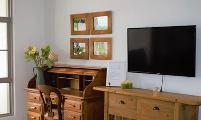 a living room with a flat screen tv on a wall at Spacious, Modern & Convenient in Franschhoek