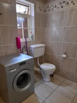 a bathroom with a toilet and a washing machine at Lovely Concordia, rental unit with free parking in Cape Town
