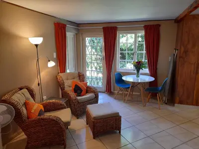 a living room with wicker chairs and a table at Lovely Concordia, rental unit with free parking in Cape Town