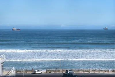 two ships in the ocean with cars parked on the beach at Ocean View 503 in Bloubergstrand