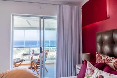 a bedroom with a bed and a view of the ocean at Whale Rock 25 in Hermanus