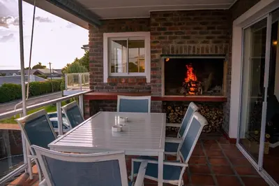 a patio with a table and chairs and a fireplace at The Mountainview Family Retreat in Hermanus