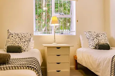 a bedroom with two beds and a lamp on a dresser at The Mountainview Family Retreat in Hermanus