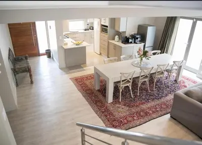 a kitchen and living room with a white table and chairs at 13 La Gratitude Luxury Apartment-with backup power for loadshedding in Stellenbosch