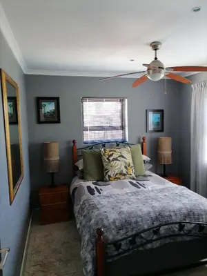 a bedroom with a bed and a ceiling fan at Somerset west Mountain road cottage in Cape Town