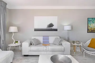 a living room with a white couch and a tree at Witsand 804 in Bloubergstrand