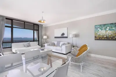 a living room with white furniture and a large window at Witsand 804 in Bloubergstrand