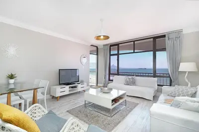 a living room with white furniture and a view of the ocean at Witsand 804 in Bloubergstrand