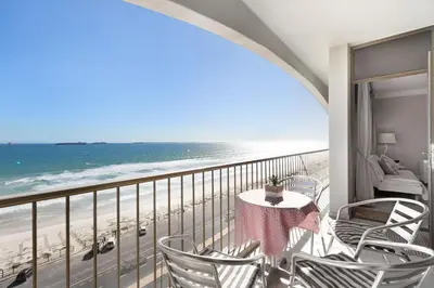 a balcony with a table and chairs and the beach at Witsand 804 in Bloubergstrand