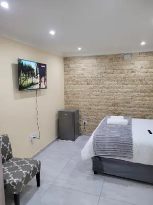 a bedroom with a bed and a tv on a wall at MIRAJO Guest House in Cape Town