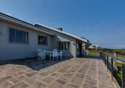 a house with a patio with a table and chairs at Seafront Retreat in Sandbaai in Hermanus