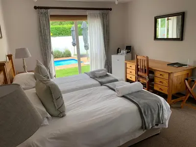 a bedroom with two beds and a desk and a window at Avenues Guest House in Stellenbosch
