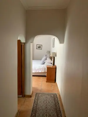 a bedroom with a bed and a table with a rug at Avenues Guest House in Stellenbosch