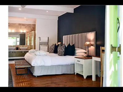 a bedroom with a large bed with pillows on it at Ashbourne Boutique Guest House in Franschhoek
