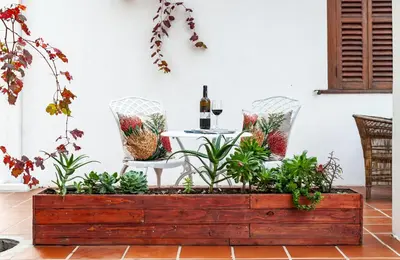 a table and chairs with a bottle of wine in a wooden box at Ayama Wine Farm - Manor House in Wellington