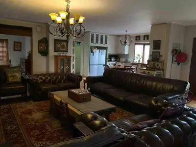 a living room with leather couches and a kitchen at 5 BEDROOM CAPE TOWN FAMILY HOME PET FRIENDLY in Cape Town