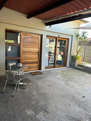 a patio with a table and a chair in front of a house at Mabel View in Cape Town