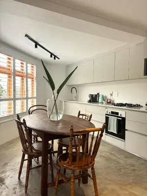 a kitchen with a wooden table with chairs and a vase on it at The Paarl Grand in Paarl