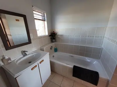 a bathroom with a tub and a sink and a mirror at Elegantie Apartment Protea 5 Lovell Avenue in Stellenbosch