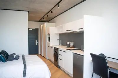 a kitchen with white cabinets and a bed in a room at 101 Bridgewater Apartment in Cape Town