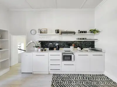 a kitchen with white cabinets and a black and white rug at Obs Loft Apartments Observatory in Cape Town