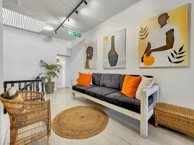 a living room with a black couch and orange pillows at Obs Loft Apartments Observatory in Cape Town