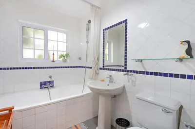 a bathroom with a sink and a toilet and a tub at Sunset Yellow Cottage in Cape Town