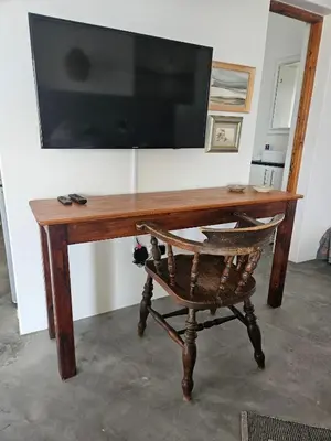 a wooden desk with a television and a chair at Suikerbos in Pringle in Pringle Bay