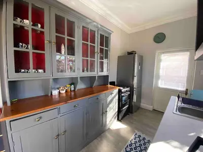 a kitchen with white cabinets and a refrigerator at Auret Street Garden Cottage in Paarl
