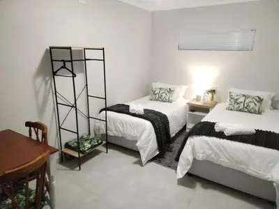 a bedroom with two beds and a table and a desk at Harmonie Self Catering in Wolseley