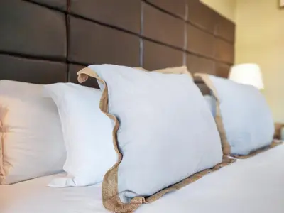 a bed with white pillows and a brown headboard at Family-Friendly Home with Ample Space in Cape Town