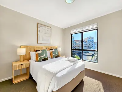 a white bedroom with a large bed and a window at Walkable, pools, park and great for families in Cape Town