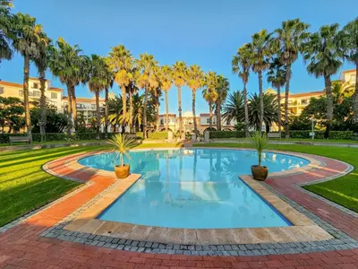 a swimming pool with palm trees in a park at Walkable, pools, park and great for families in Cape Town