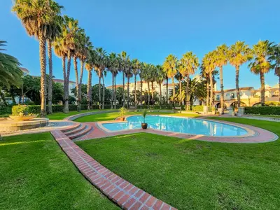 a swimming pool in a park with palm trees at Walkable, pools, park and great for families in Cape Town