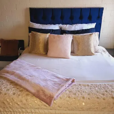 a large bed with gold pillows and a blue headboard at Mercy's Getaway Place in Cape Town